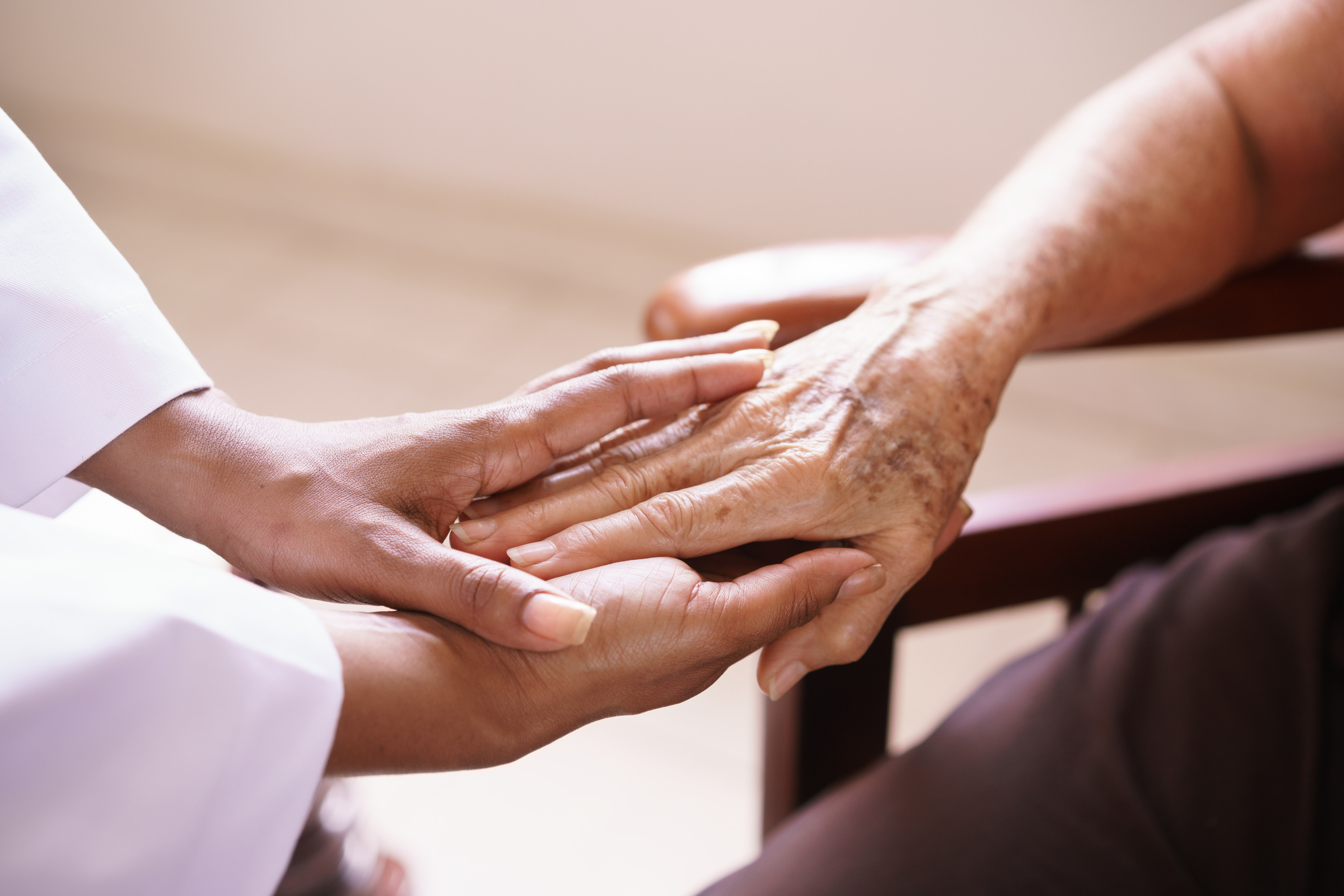 A caregiver gently holding an older adult’s hands